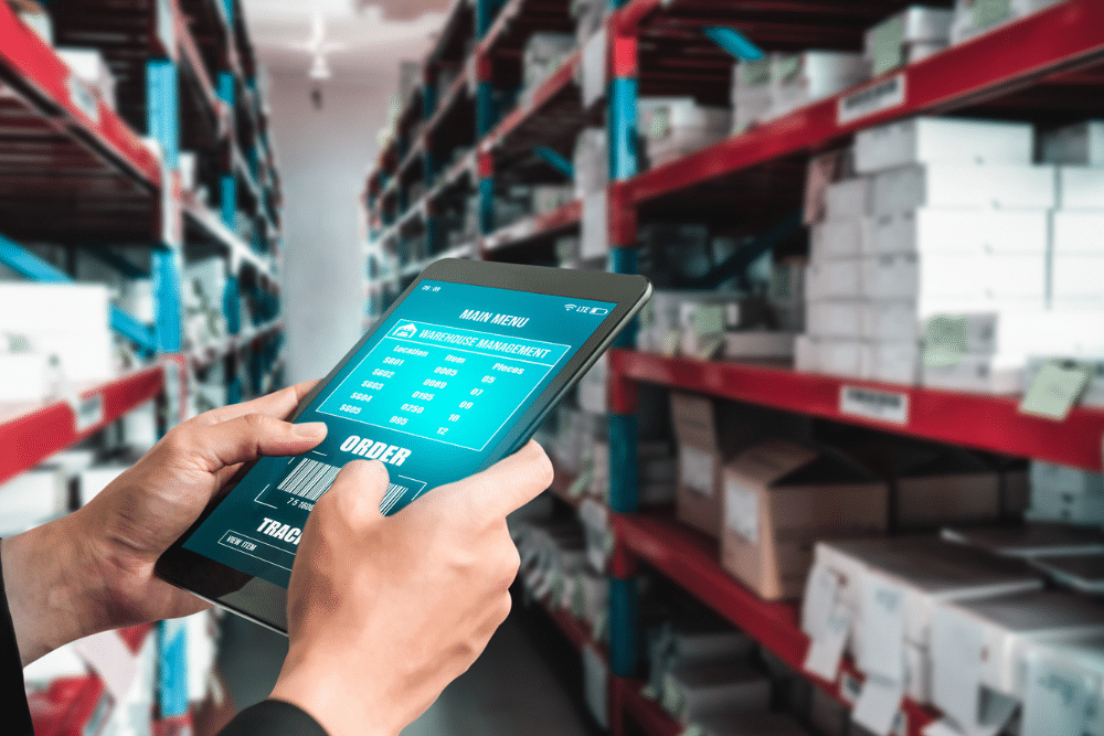 Photo of someone using a tablet device in a warehouse with a digital inventory management tool