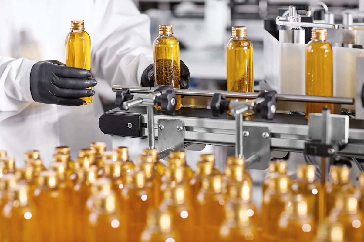 Closeup of a manufacturing worker bottling cosmetics in a factory.