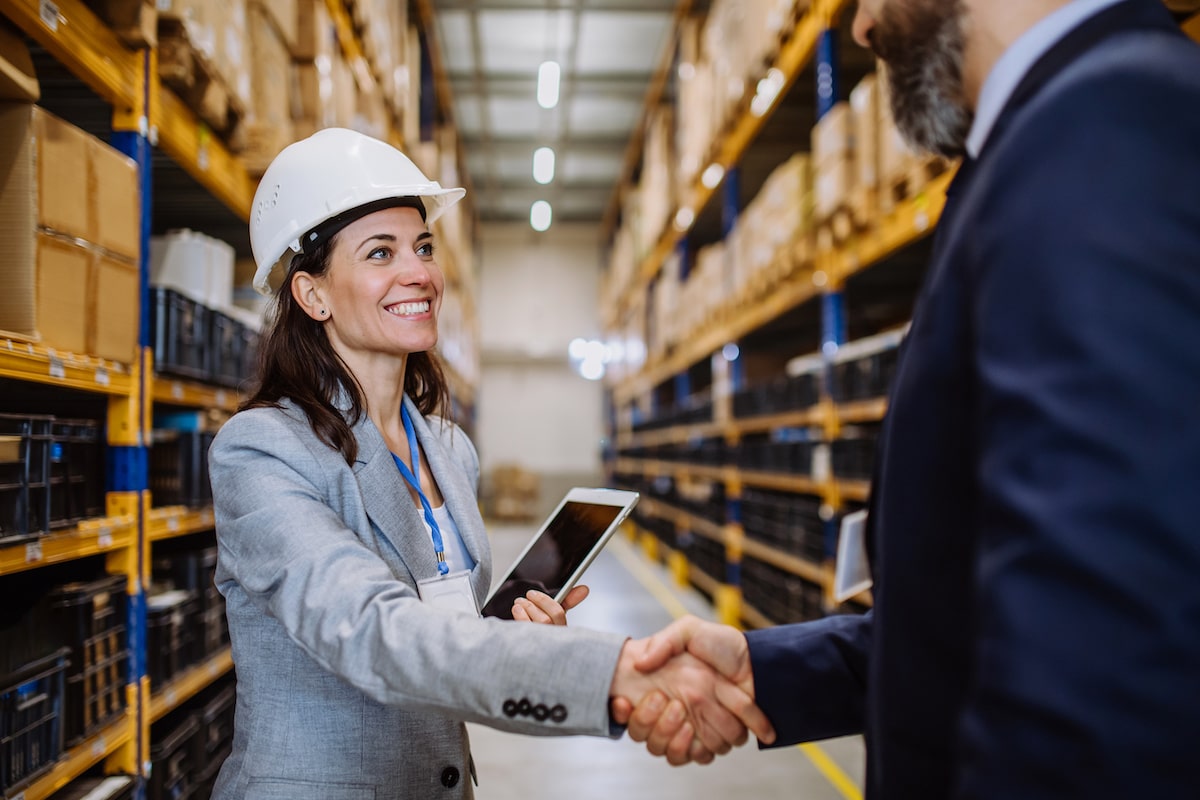 A warehouse manager shaking hands with a man in a suit